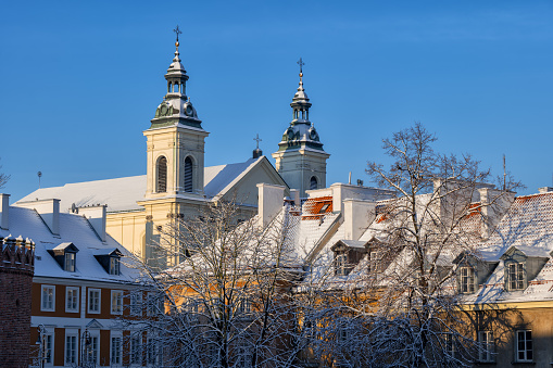 Winter in the New Town (Nowe Miasto) of Warsaw city in Poland, snowy roofs of church and historic tenement houses.