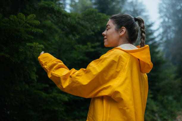 Never mind the rain, have fun anyway Female in yellow raincoat hiking through mountain on a rainy day. anyway stock pictures, royalty-free photos & images