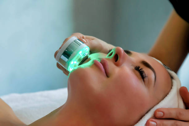 estetista che fa terapia della luce a led alla donna nel salone spa, fototerapia facciale per la pulizia dei pori della pelle - laser therapy medical laser light therapy foto e immagini stock