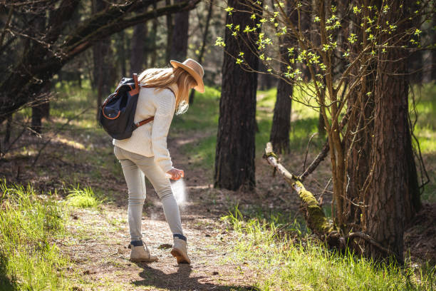 mujer rociando repelente de insectos contra garrapata en su pierna en el bosque - insect repellant mosquito bug bite spraying fotografías e imágenes de stock