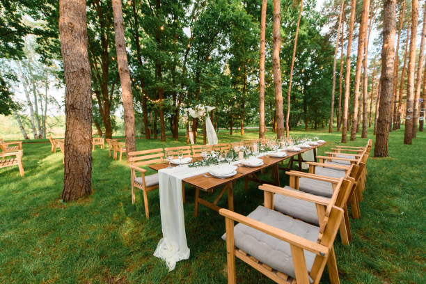 istock Wedding table with rustic decoration in the forest. Plates, and green branch with candles on the table. Green decoration 1318493629