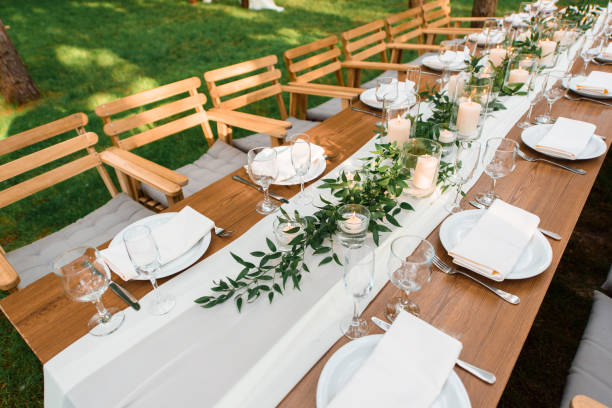 istock Wedding table with rustic decoration in the forest. Plates, and green branch with candles on the table. Green decoration 1318493662