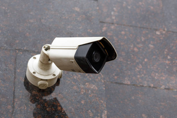 small cheap surveillance camera on tan brown granite wall