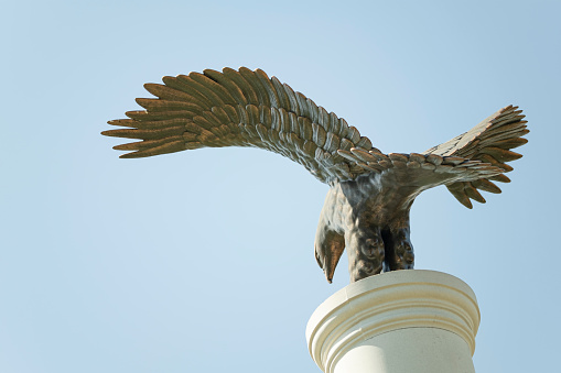Eagle stone statue on blue sky.