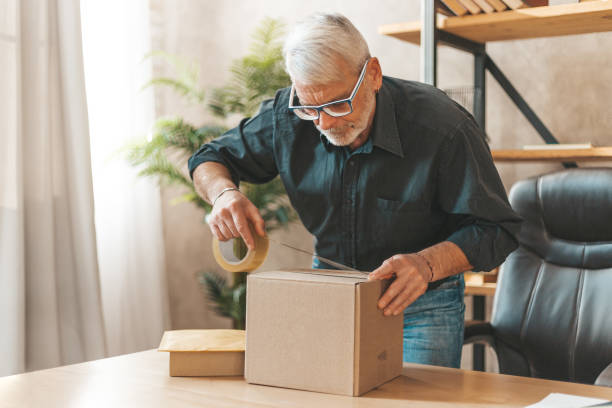 Seal the parcel. A grown man sends a box of goods by mail. Return of purchase to the online store Seal the parcel. A grown man sends a box of goods by mail. Return of purchase to the online store. returning stock pictures, royalty-free photos & images