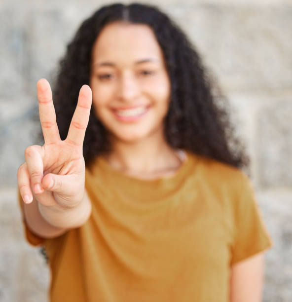 foto de una mujer mostrando el signo de la paz mientras estaba de pie afuera - two fingers fotografías e imágenes de stock