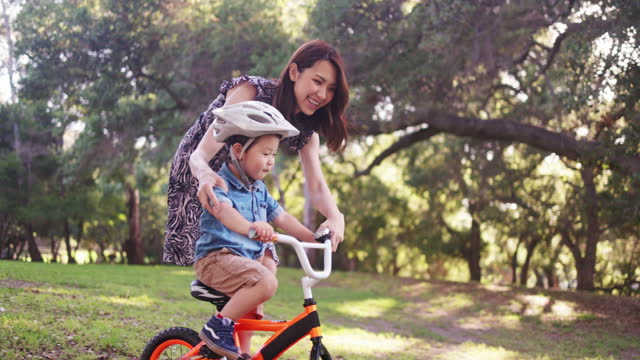 Mom Helping Son Riding a Bicycle in the park