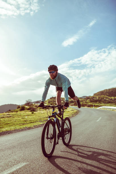 istock Modern Male Cyclist Performing Tricks While Riding Down Mountain Asphalt Road 1318502394