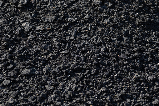 The background is the texture of small black fragmented stones in the form of asphalt crumbs. A lot of building material for industrial repair of black coal roads. High quality photo
