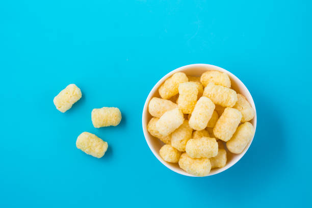 istock Corn sticks in powdered sugar in a bowl on a blue background. Top view 1318503603