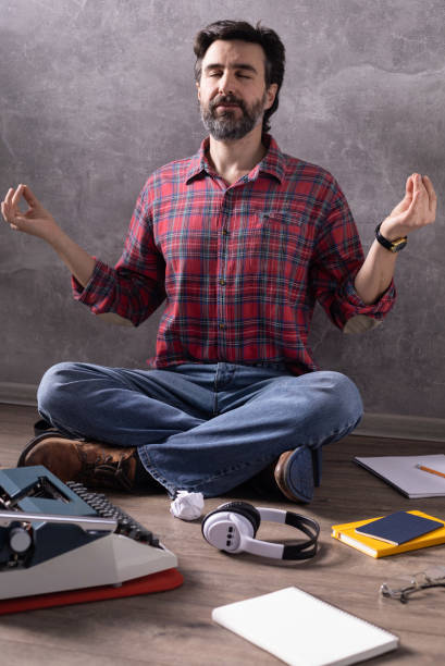istock Man meditating on floor thinking idea or relaxing. Writer or screenwriter with typewriter and paper. Creative concept 1318505236