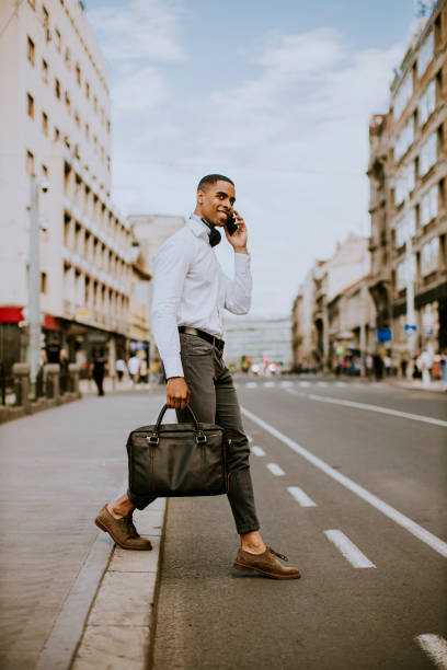 istock Young African American businessman using a mobile phone while crossing a street 1318505296