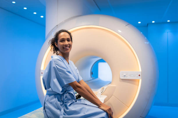 patientin sitzt vor der mrt-scan auf dem bett - magnetresonanztomographie stock-fotos und bilder