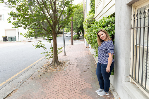 a single woman in her 40's outside exploring the city of Savannah, Georgia in the spring looking at the camera and smiling
