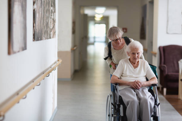 Caregiver helping senior woman in wheelchair stock photo