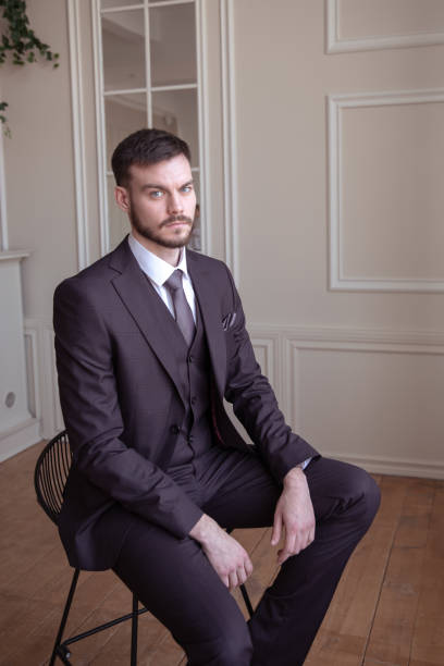 istock beautiful young man with a beard brunette model. guy in a classic suit in a light stylish interior. 1318508345