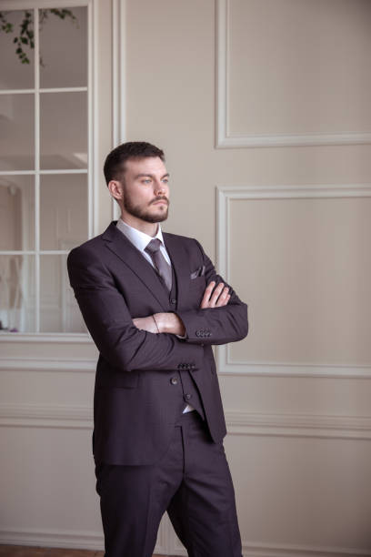 istock beautiful young man with a beard brunette model. guy in a classic suit in a light stylish interior. 1318508365