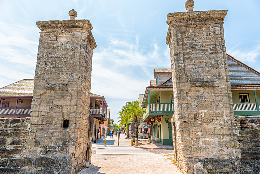 St. Augustine, USA - May 10, 2018: Saint George Street and people walking on sunny day by stores in downtown old town Florida city with stone gate entrance