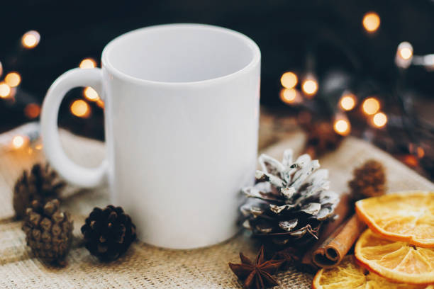 istock White empty cup and pine cones, anise, cinnamon, dried oranges on background of christmas lights 1318513583