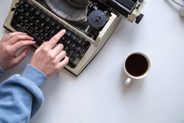 istock Woman's hand typing on a vintage typewriter top view. 1318514903