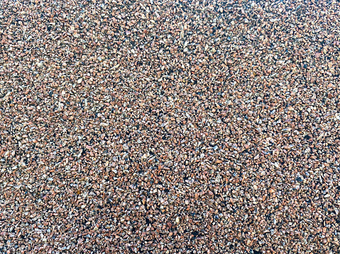 The texture of a gouged rough stone surface with small sharp stones of different colors. The background.