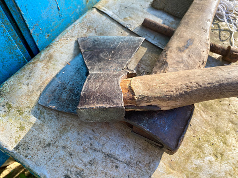 Set of iron tools ax hammer close-up old wooden handle weathered on boards.