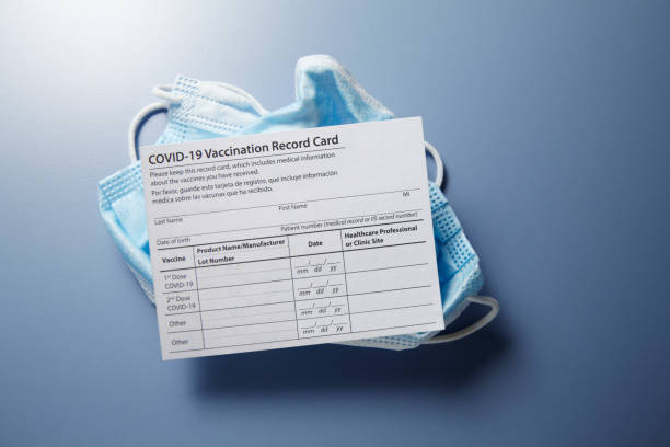 istock COVID-19 Vaccination Card On Discarded Protective Face Mask 1318519561