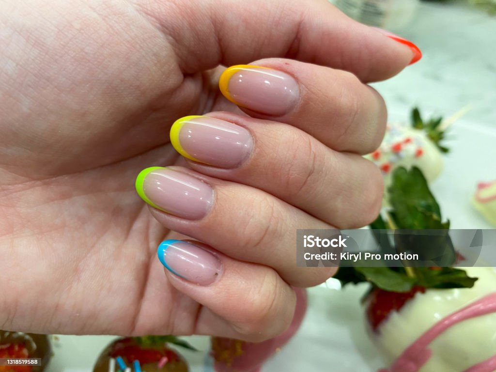 虹透明の黄色い赤い緑の青の異なる色のゲルニスと指の美しい多色の女性のマニキュアファッショナブルなスタイリッシュなフランス語。スタイリッシュなネイルデザイン - 手の爪のロイヤリティフリーストックフォト