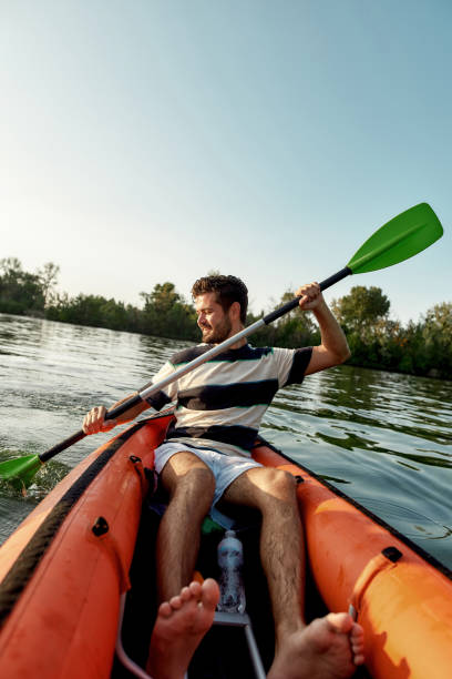 istock Active young man looking enthusiastic while kayaking in a lake, surrounded by peaceful nature on a summer afternoon 1318520516