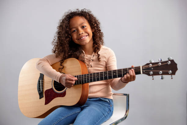 Young Girl Playing The Guitar And Looking At Camera stock photo