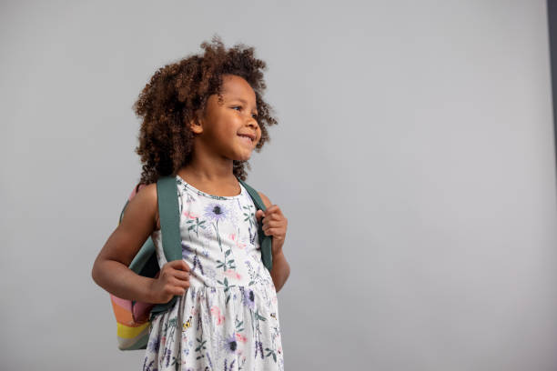 istock Little Girl With Backpack Standing On White Background 1318524634