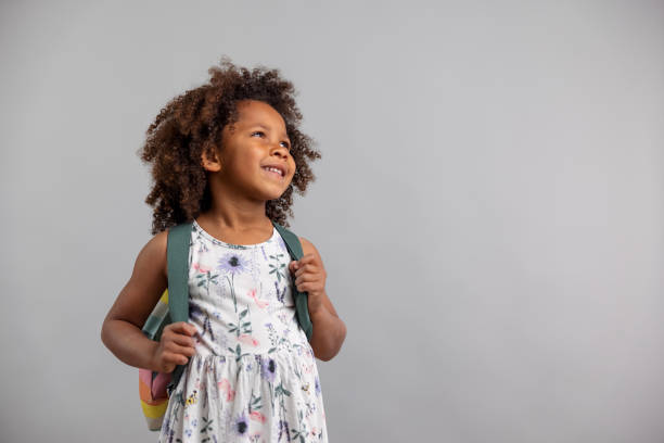 Little Girl With Backpack Standing On White Background