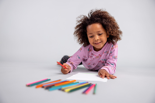 Young Girl Drawing With Color Pencils On The Floor