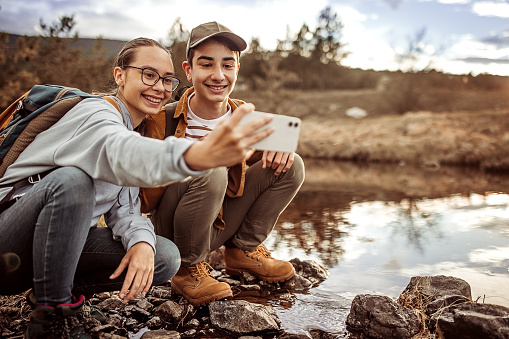 Teenage girl and boy enjoys and make a selfie in the nature