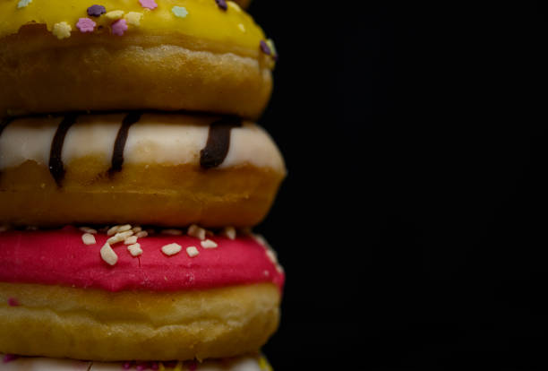 Donuts of multiple colors piled up close up