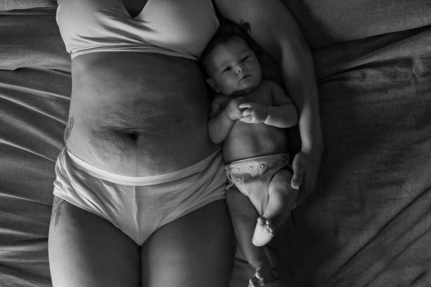 un bébé se pose à côté de l’estomac de ses mères - body women naked beauty photos et images de collection