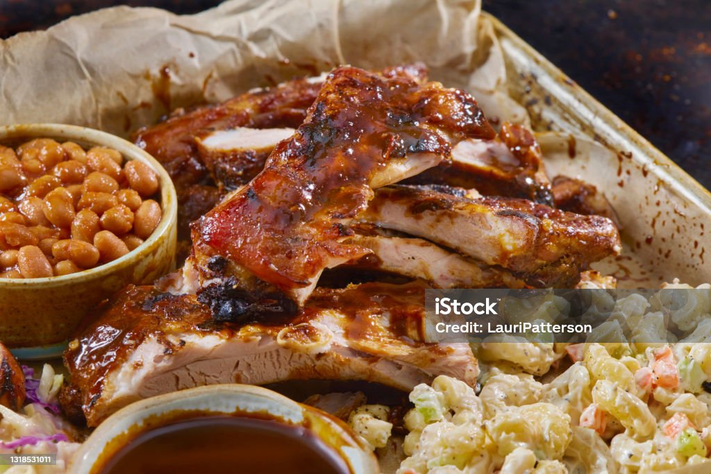 BBQ Pork Ribs Plater BBQ Baby Back Pork Ribs with Sausage, Baked Beans, Creamy Coleslaw and Macaroni Salad Barbecue - Meal Stock Photo