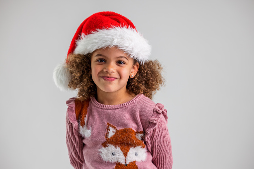 Portrait Of A Young Girl Wearing A Santa Hat And Looking At Camera