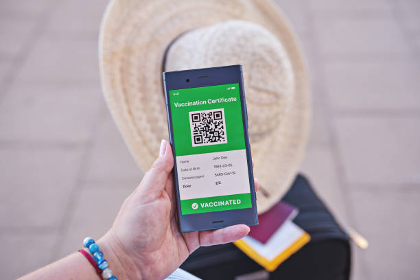 istock Smartphone in hand displaying on app mobile valid digital green vaccination certificate for Covid-19. 1318532106