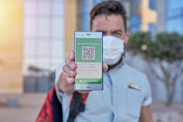 istock Man holding smartphone displaying on app mobile valid digital green vaccination certificate for Covid-19. 1318532151