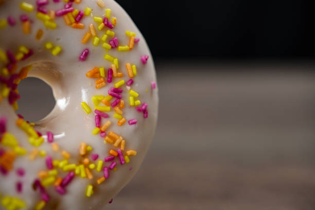 Delicious white donut with colorful sprinkles on table, close up. High quality photo