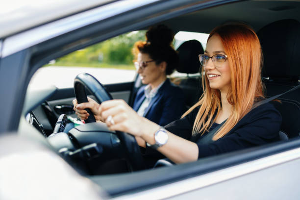 Driving school or test. Beautiful young woman learning how to drive car together with her instructor. stock photo