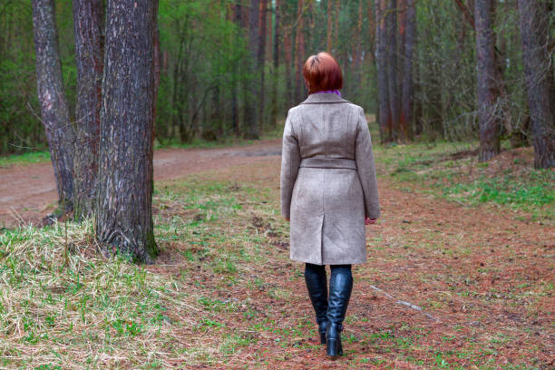 istock woman in coat and boots walks through the forest in spring 1318537823