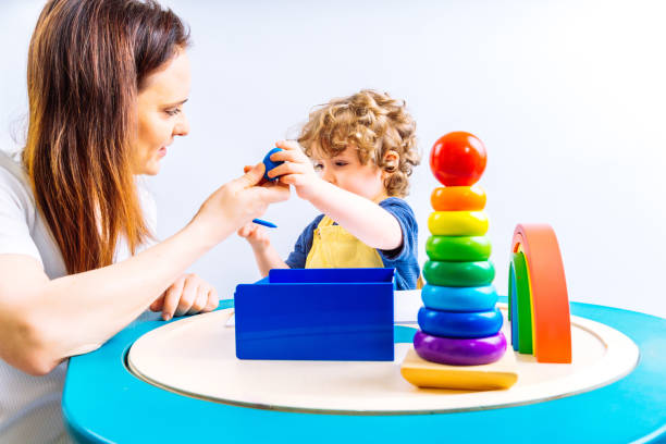 istock three year old boy and his mother playing on a montessori learning table with colorful paints on white background. home learning concept. home school 1318550913