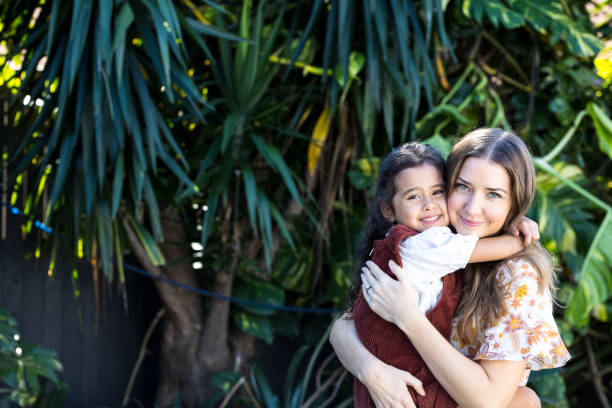 Happy Mother and Young Daughter Embracing In Backyard