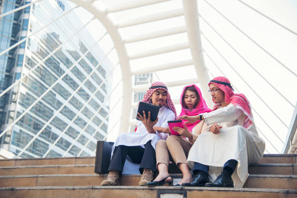 istock Digital marketing group arab people using smart tablet walking in  modern muslim UAE city touch screen discussion. Entrepreneur Asian people smile talking with boss outdoors 1318558636