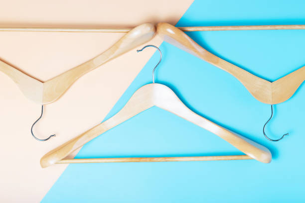 istock Three empty wooden hangers on brown and blue background close-up. 1318558766