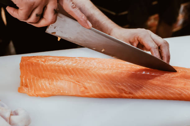 istock Professional chef preparing a fresh salmon on a cutting board. 1318561219