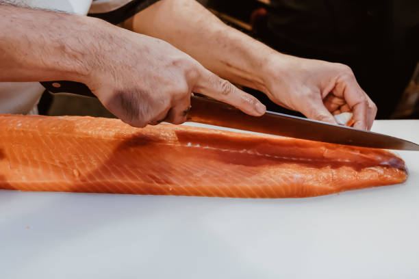 istock Professional chef preparing a fresh salmon on a cutting board. 1318561232