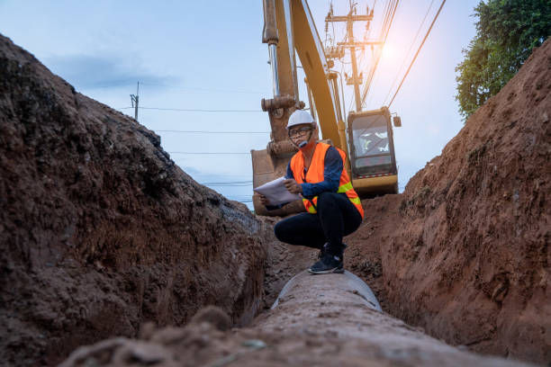 Engineer wear safety uniform examining excavation water supply or sewer pipeline Engineer wear safety uniform examining excavation water supply or sewer pipeline at construction site. digging stock pictures, royalty-free photos & images